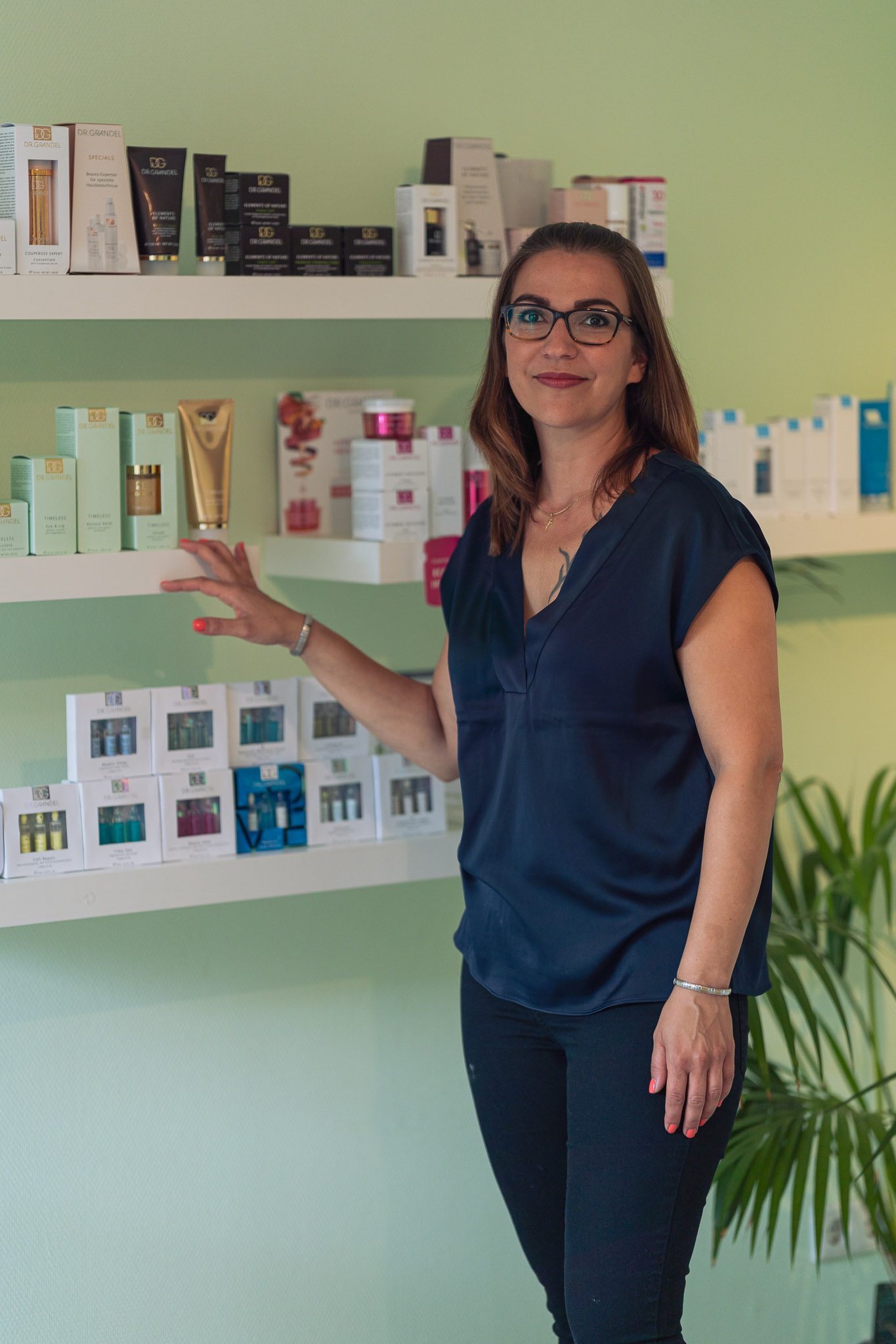 Janine Grall Janine Grall steht vor einem Wandregal mit Kosmetik